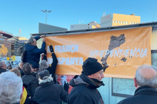 Manifestantes contra la cumbre hispano francesa cuelgan un cartel, foto: Pedro Ruíz